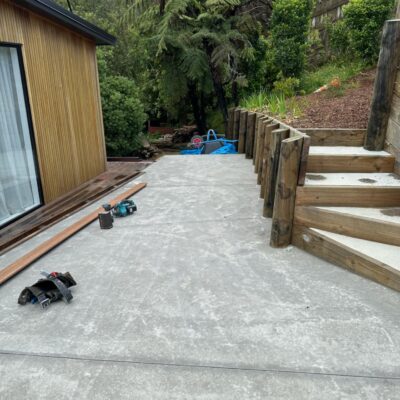 Construction area beside timber pool house with exposed concrete pathway and retaining work completed by Total Build Wellington.