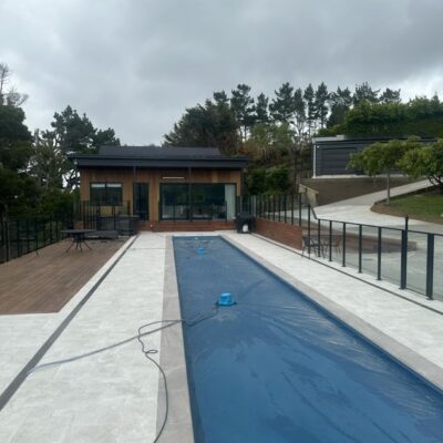 Landscaped walkway and glass fencing overlooking a long lap pool at a Wellington renovation by Total Build Wellington.