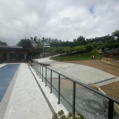 Full-length view of modern lap pool with tiled coping and pool house in the background built by Total Build Wellington.
