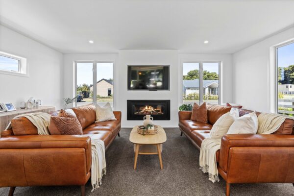 Light-filled living room with leather sofas and central fireplace in a contemporary Wellington new build by Total Build Wellington.