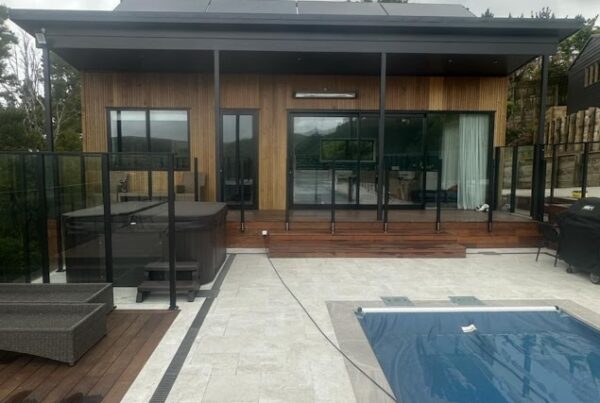 Architectural timber-clad pool house in Wellington with glass fencing and tiled outdoor area built by Total Build Wellington.