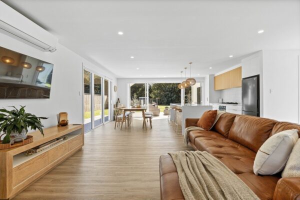 Contemporary lounge, dining and kitchen space with full-height glazing and timber flooring, completed as part of a Wellington design and build project.