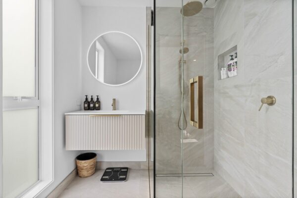 Modern bathroom renovation with round LED mirror, vessel basin and brass tapware installed by Total Build Wellington.