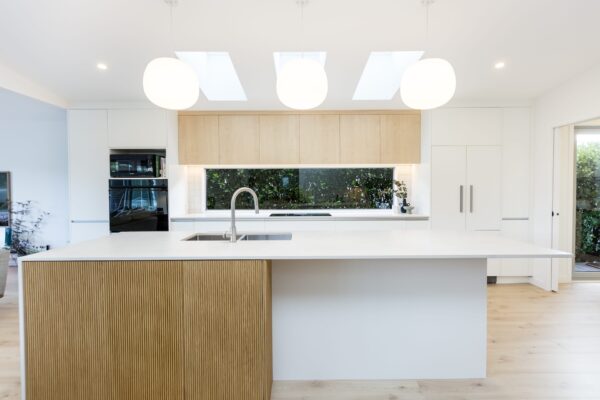 A contemporary kitchen with a large island, skylights, and timber cabinetry, demonstrating modern house designs and architecture house design found in new build homes, including 3 bedroom house designs and architectural builds.