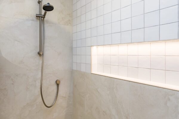 A tiled walk-in shower with a rainfall shower head and built-in niche, highlighting luxury bathroom details found in architecture house design and quality home construction for new builds.