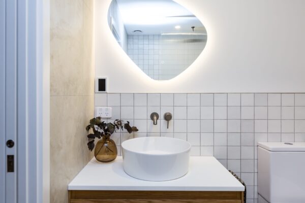 A close view of a modern bathroom vanity and illuminated mirror, showcasing stylish finishes ideal for small house design, architecturally designed homes, and premium new builds.